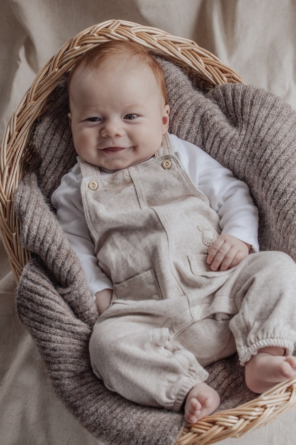 Nyfødt baby sidder i en fletkurv med tæppe omkring sig